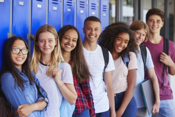 Teenage school kids smiling to camera in school corridor