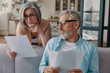 Busy senior couple in casual clothing taking care of their finances while bonding together at home