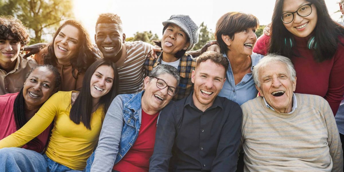 Group of multigenerational people smiling in front of camera - Multiracial friends od different ages having fun together - Main focus on caucasian senior faces