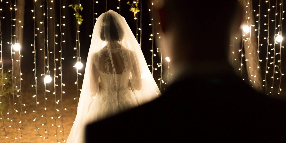 Wedding ceremony night. Meeting of the newlyweds, the bride and groom in the coniferous pine forest of candles and light bulbs.