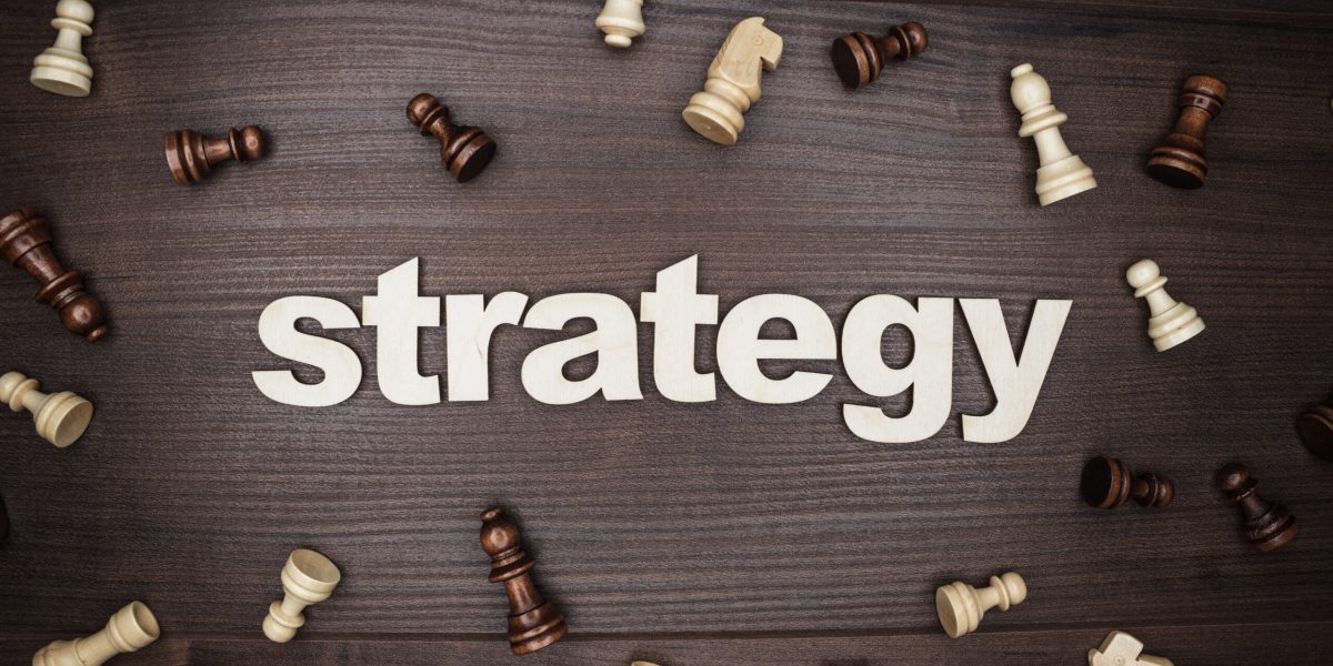 word strategy and chessmen on the brown wooden background
